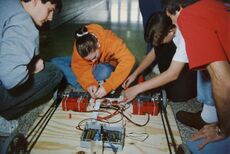 Team 45 wiring the 1997 control system, showing an RNet radio plugged into the receiver box, two drill battery holders, two drill motors, and two Tekin speed controllers [9]